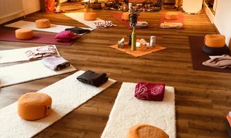 A quiet yoga room with mats, pillows, and a pleasant atmosphere. The walls are adorned with decorative elements that create a relaxing mood.