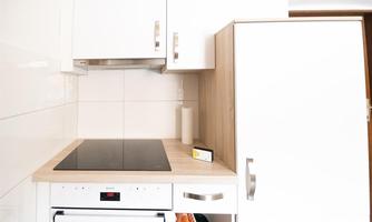 A modern kitchen with white cabinets and a wooden countertop. The stove and the refrigerator are clearly visible.