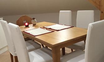 A cozy wooden dining table with six chairs in a bright room. The atmosphere is warm and inviting, perfect for social gatherings.
