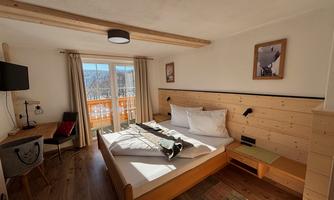 A cozy and modern bedroom with a large bed and wooden furniture.  
Large windows provide a nice view outside.