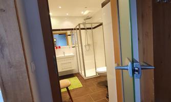 A modern bathroom area with a shower and bright walls. The door openings reveal a clean and well-lit atmosphere.