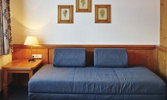 A simple room with a blue couch and a small table. Three framed pictures are hanging on the wall.