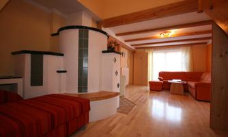 A modern living room with a cozy atmosphere. There is a seating area in orange and a tiled stove.
