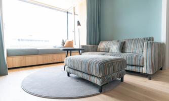 A modern living room with a striped sofa and an ottoman. Large windows provide plenty of light and a beautiful view.