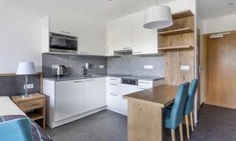 A modern kitchen unit with white cabinets and a dining area. The surroundings are bright and inviting.