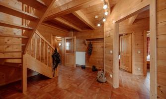 A rustic entrance area made of wood with a staircase. The room is well-lit and has an inviting character.