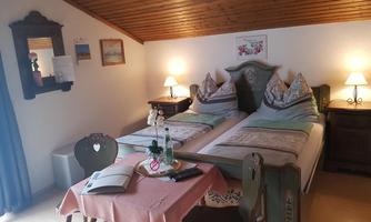 A cozy bedroom with two single beds and wood paneling. On the table, there is a vase of flowers and a magazine.