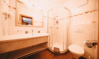 A modern bathroom with a shower cubicle, a sink, and a toilet. The walls are brightly tiled and there is a large mirror.