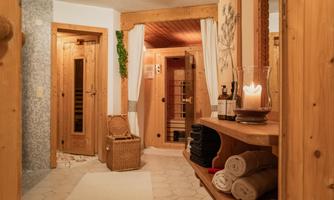 A cozy wellness area with wooden paneling. In the room, there are saunas, towels, and a candle on a shelf.
