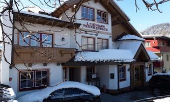 A charming country house named "Berekenbach," covered in snow. The architecture is traditional and inviting, surrounded by a wintry landscape.