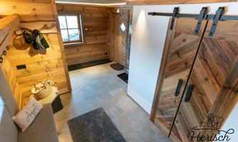 A cozy entrance area with wood paneling and large sliding doors. The room is bright and inviting, perfect for a rustic style.