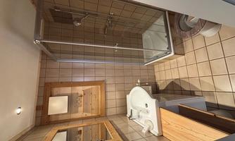 A small bathroom with a shower cabin, a sink, and a toilet. The walls are tiled, and wood details create a warm atmosphere.