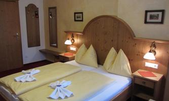 A cozy bedroom with bright wood paneling. Two beds are adorned with yellow bed linens and towels.