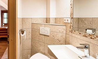 A modern bathroom with bright tiles and an elegant sink. The furnishings are simple and functional, with a large mirror.