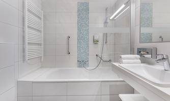 A modern bathroom with a bathtub and a shower. The walls are tiled in white, and a blue accent wall adds a fresh look.