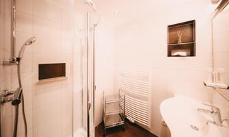 A modern bathroom with a shower cubicle and a sink. Bright tiles and a towel rack create a pleasant atmosphere.