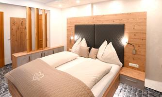 A modern bedroom with a double bed and a wooden design. The walls are light and well-lit, creating a cozy atmosphere.