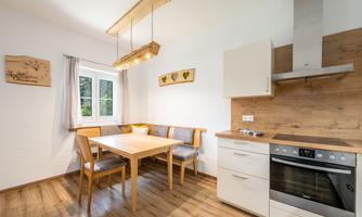 A bright kitchen with a wooden table and chairs. The walls are painted in soft colors and there are modern kitchen appliances.