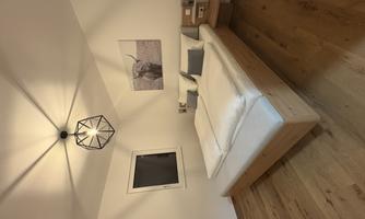 A modern bedroom with a double bed and two pillows. A picture of an animal hangs on the wall, and the room features a wooden floor.