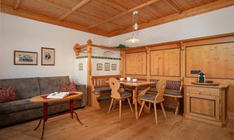 A cozy room with wood paneling and a dining table. A sofa corner invites you to relax.