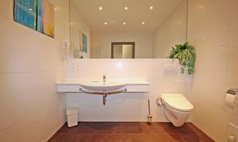 A modern bathroom with a bright sink and elegant tiles. The walls are light and there is a small plant decorative accent.