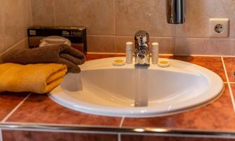 A modern sink with various towels and toiletries. The tiles are in warm colors.