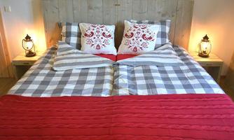 A cozy bedroom with a large bed and stylish pillows. Decorative lanterns stand next to the bed to create a warm atmosphere.