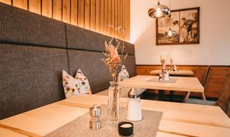 A cozy restaurant with wood paneling and stylish tables. On the tables, there are flower vases and salt shakers.