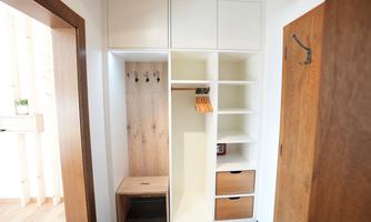 A modern coat area with wooden shelves and hooks. The combination of white and wood-colored elements creates a bright and inviting atmosphere.