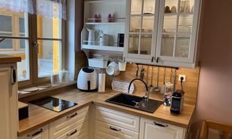 A modern kitchen with white cabinets and wooden surfaces. The kitchen equipment is neatly and functionally arranged.