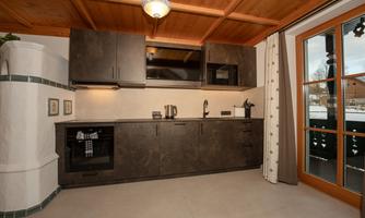 A modern kitchen with dark cabinets and a large window front. There is a stove, a sink, and space for kitchen appliances.
