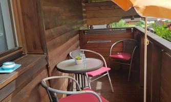 A cozy balcony with a round table and two chairs. A large umbrella provides shade and a relaxed atmosphere.