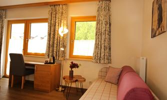 A cozy interior with a sofa and a table. Large windows allow plenty of natural light to come in.