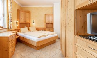 A cozy bedroom with wooden furniture and a double bed. The walls are painted in warm colors and the room feels inviting.