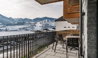 A balcony with a view of snow-capped mountains and a picturesque landscape. The sky is clear, and the surroundings are calm and inviting.