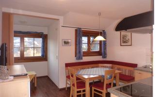 A cozy dining area in a modern kitchen. Windows allow plenty of light in and offer a view outside.