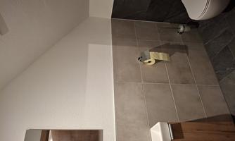 A modern bathroom with a simple design. There is a sink, a toilet, and a large mirror.