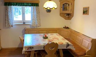 A cozy dining area with a wooden bench and table. The window lets in plenty of light and the decoration is rustic.