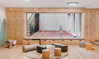 A bright and inviting room with wood paneling and a large window. Outside, a child is playing on a sports field with a soccer ball.