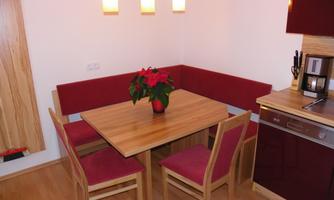 A modern kitchen with a wooden desk and red furniture. On the table, there is a bouquet of flowers in a vase.