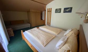 A cozy bedroom with a double bed and an additional sofa bed. The walls are painted in light colors and there are decorative pictures on the wall.