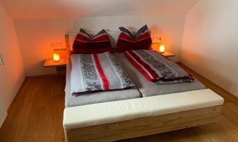 A cozy bedroom with a double bed and decorative cushions. Soft light from two table lamps creates a relaxing atmosphere.