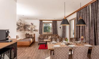 A modern living and dining room with cozy furnishings. Large windows and stylish decor create an inviting atmosphere.