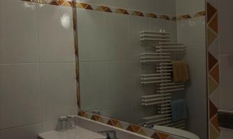 A modern bathroom with a sink and a large mirror. Towels and a towel rack are mounted on the wall.