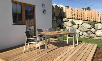 A cozy outdoor area with a wooden table and chairs. The terrace is surrounded by a well-maintained garden and has a friendly atmosphere.
