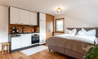 A modern, cozy accommodation with a sleeping area and a fully equipped kitchenette. The room features bright colors and wooden details that create an inviting atmosphere.