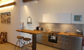 A modern kitchen with stainless steel appliances and a wooden countertop. Bright walls and cozy lighting create an inviting atmosphere.