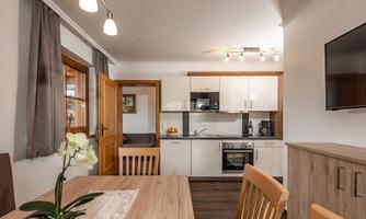 A modern kitchen with a dining area and wooden furniture. The room has large windows and a cozy atmosphere.