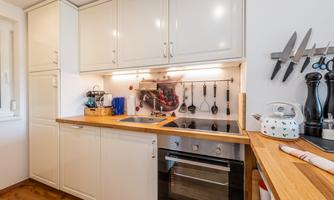 A modern kitchen with light cabinets and a wooden countertop. The equipment includes a stove, an oven, and various kitchen appliances.