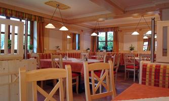 A cozy restaurant with wooden chairs and a red-checkered tablecloth. Large windows let in plenty of light and create a pleasant atmosphere.